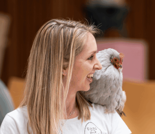 Grey chicken sitting on woman's shoulder