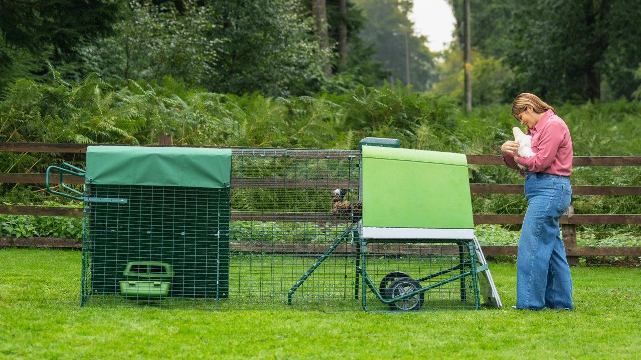Woman holding chicken outside of her modern chicken coop