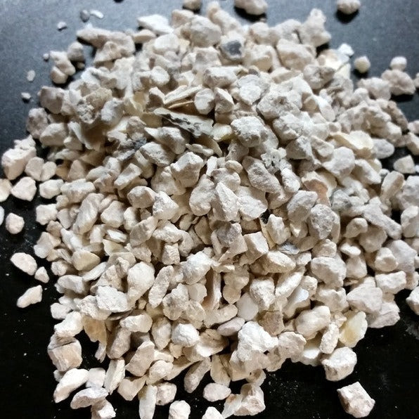 A pile of crushed oyster shell intended as a calcium supplement for poultry.